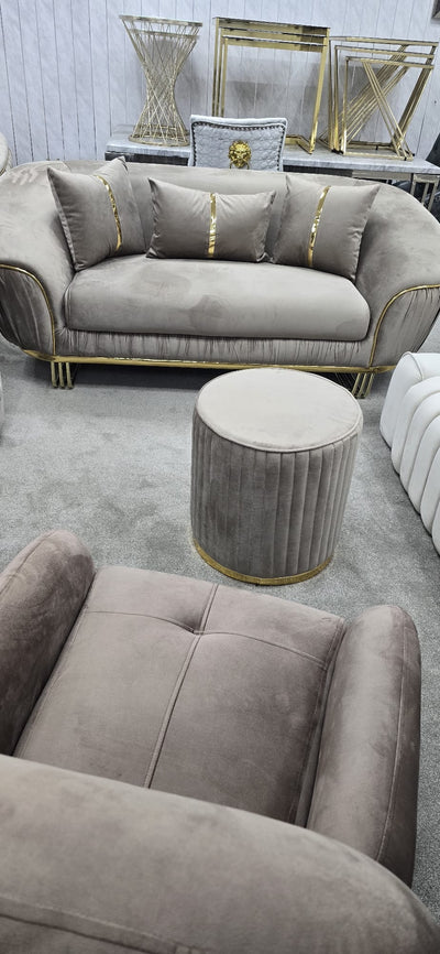 Beige sofa with decorative pillows and a matching ottoman in a room setting.