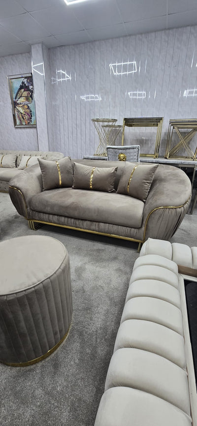 Beige sofa with gold accents in a room with grey walls and a rug.